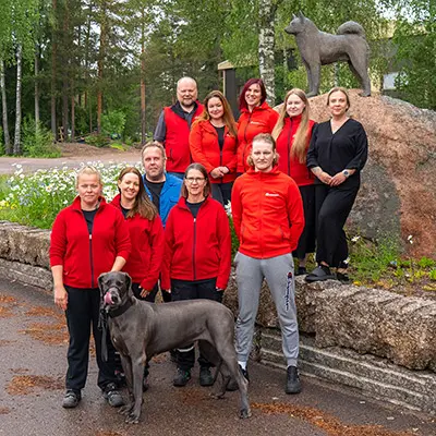 Työntekijöitä seisomassa Kennel-Rehun pihalla. Kuvassa myös koirapatsas sekä yksi tanskandoggi